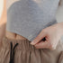 Person wearing a gray knitted top with text on a beige background